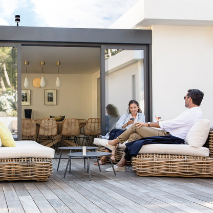 Netatmo Smart vejrstation app vist på telefon udendørs ved terrasse, moderne hus i baggrunden, loungeområde.