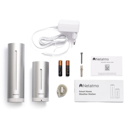 Netatmo Smart vejrstationskit med to sølvfarvede sensorer, strømforsyning, AAA-batterier, skruer, USB-kabel og manual.