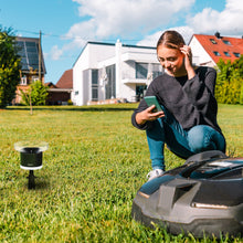 Netatmo Regnsensor til Netatmo vejrstation synlig på græsplæne ved siden af robotplæneklipper.