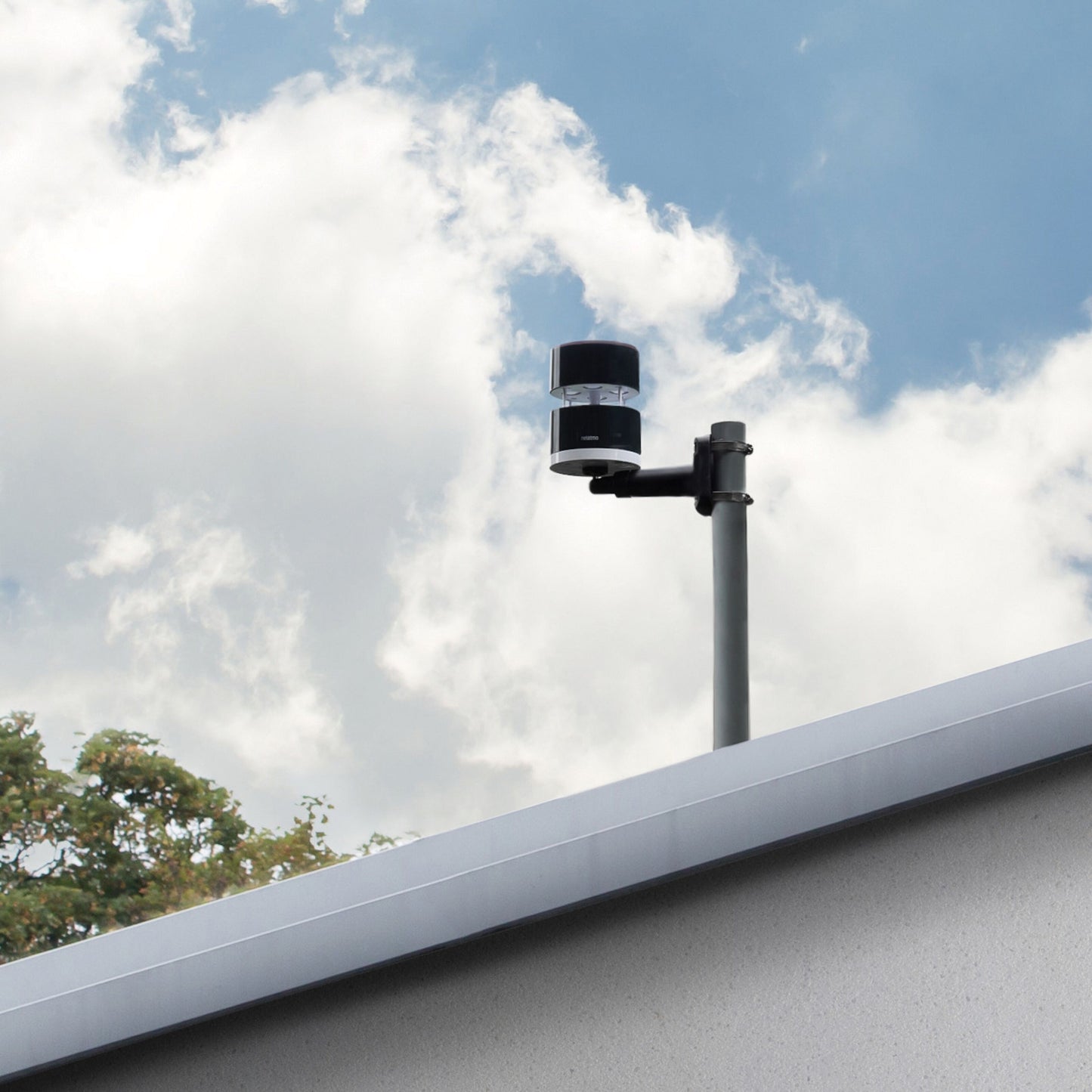 Netatmo Anemometer vindmåler til Netatmo vejrstation monteret på metalstang over hvidt tag, blå himmel i baggrunden.