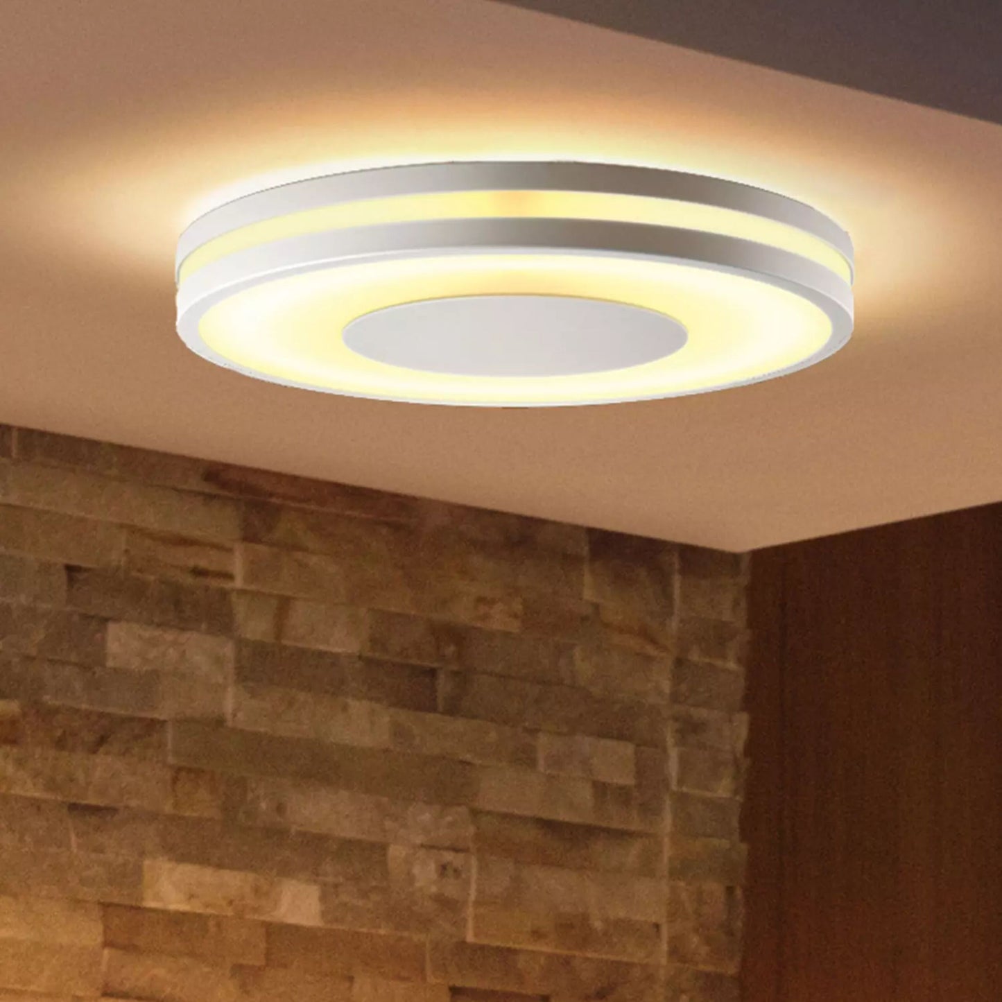 Philips Hue Ambiance Being loftslampe med dæmper, varm justerbar LED-lys, monteret i loft over lys brun stenvæg.