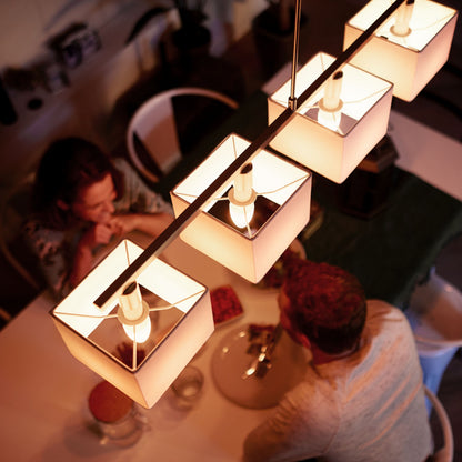 Fire firkantede pendellamper med Philips Hue Color Ambiance Smart LED-pære E14 470 lm over spisebord med grøn dug.