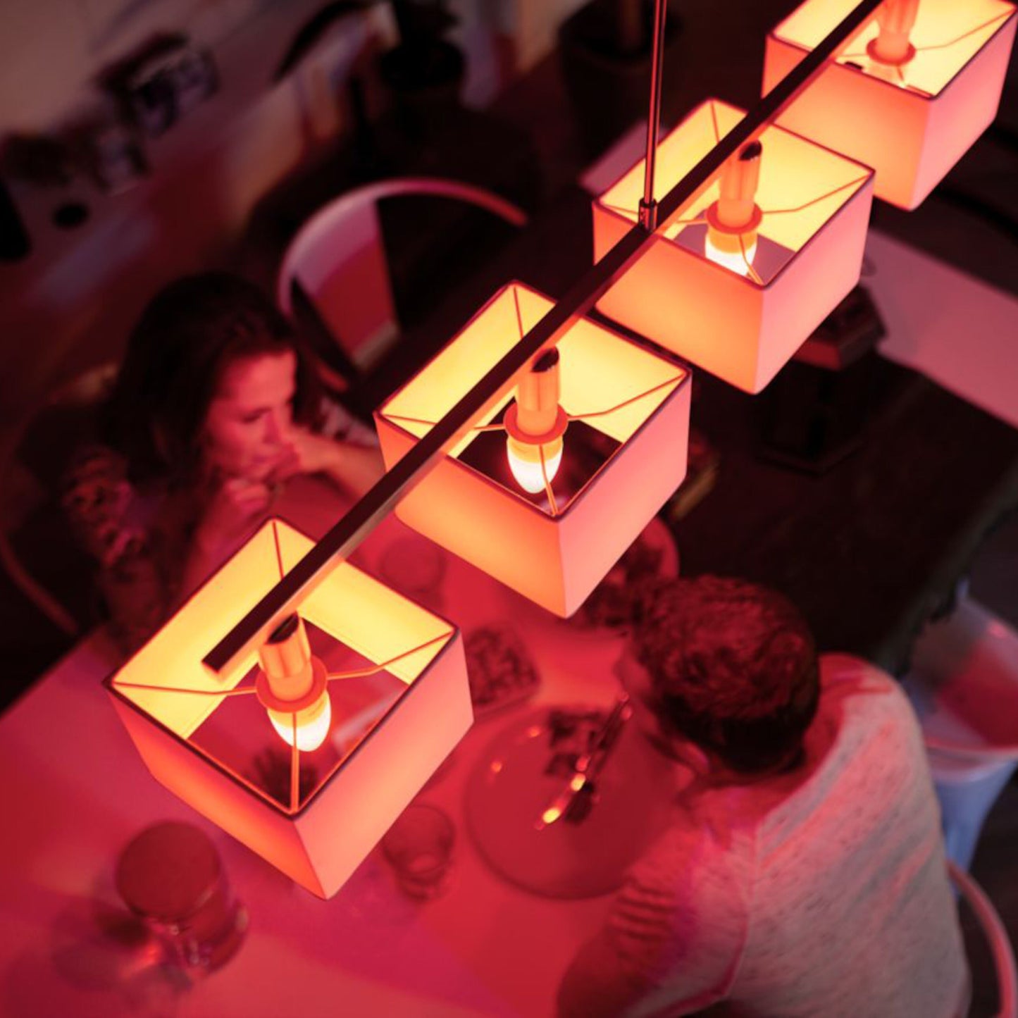 Philips Hue Color Ambiance Smart LED-pære E14 470 lm 2-pack monteret i firkantede pendellamper over spisebord.