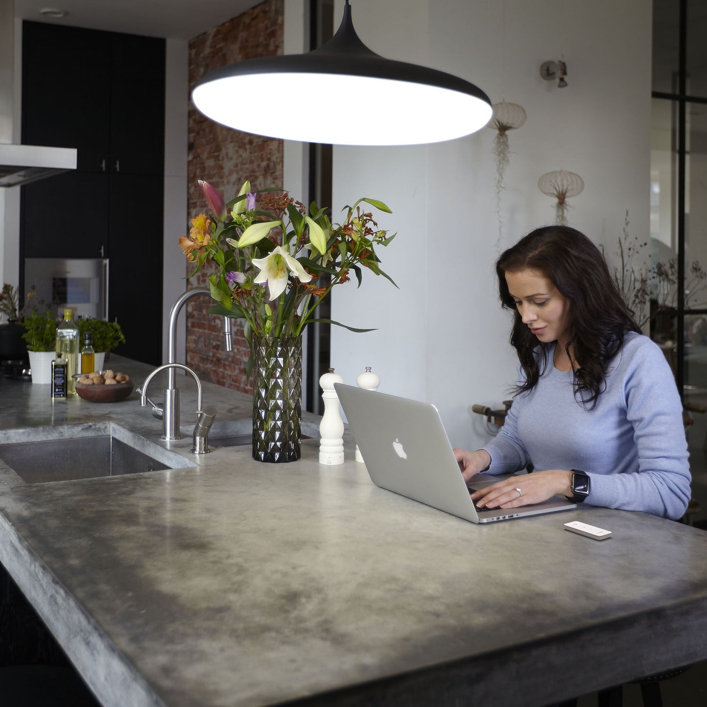 Philips Hue Dim Switch v2 Fjernbetjening hvid på beton køkkenø ved laptop med blomster og smartphone under stor lampe.