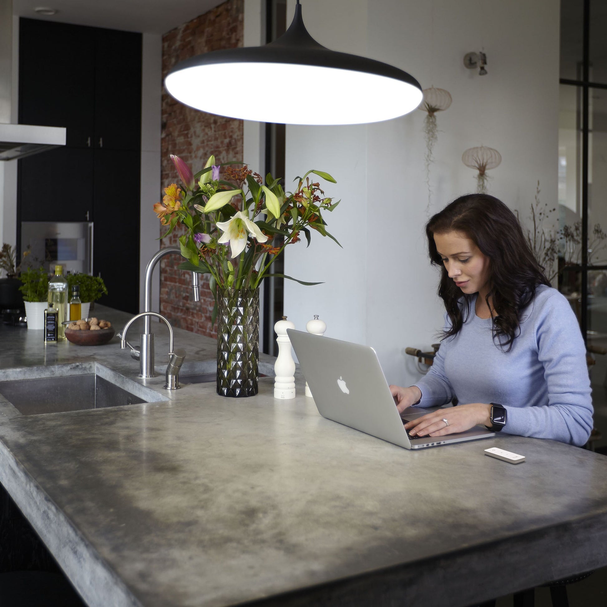 Philips Hue Dim Switch v2 Fjernbetjening hvid på beton køkkenø ved laptop med blomster og smartphone under stor lampe.