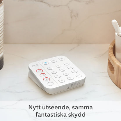 Ring Alarm 2. gen tastatur i hvid på bord, svensk tekst: Nytt utseende, samma fantastiska skydd.