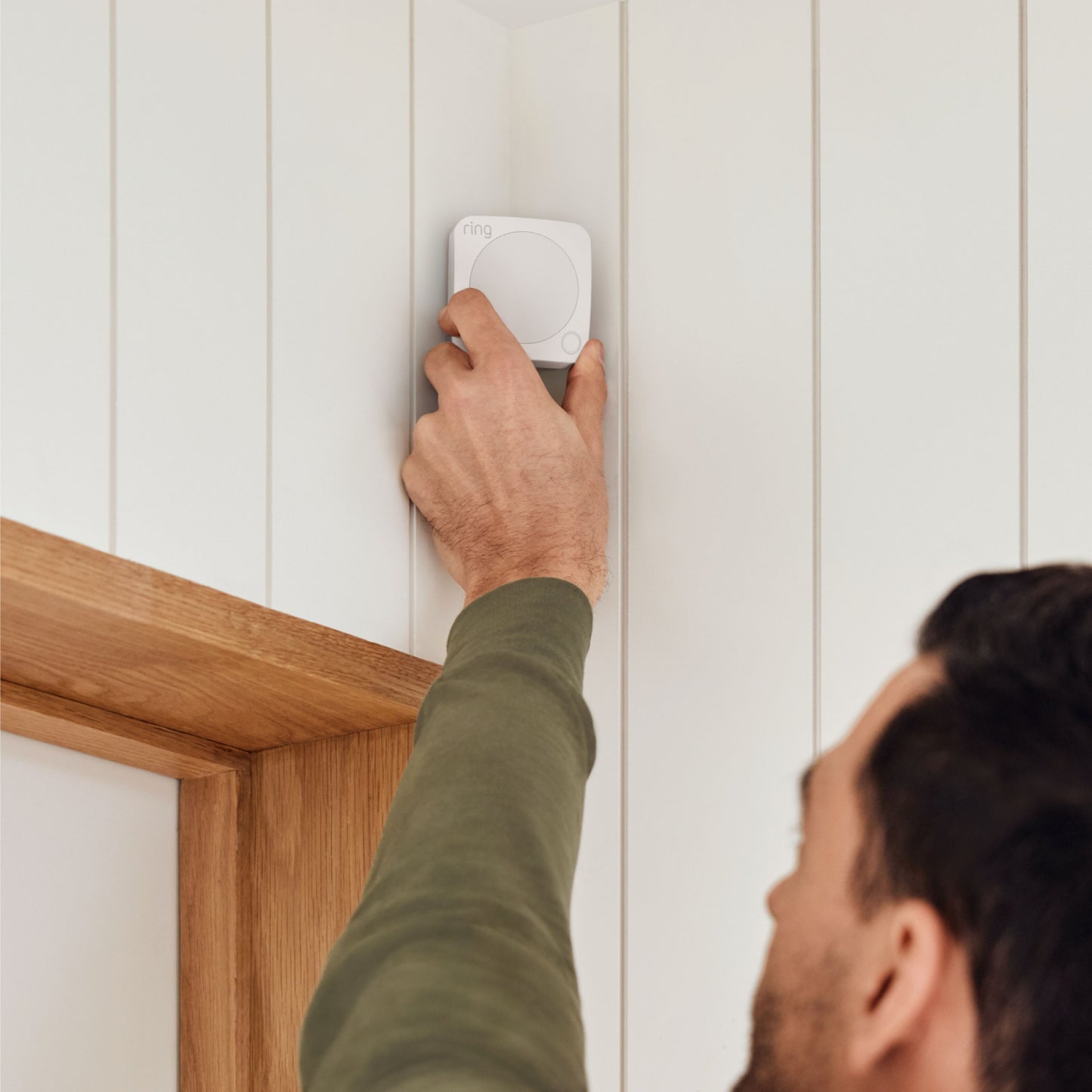 Ring Alarm 2. gen alarmsystem, kompakt firkantet enhed på hvid væg over trædørkarm, Z-Wave smart home-enhed.