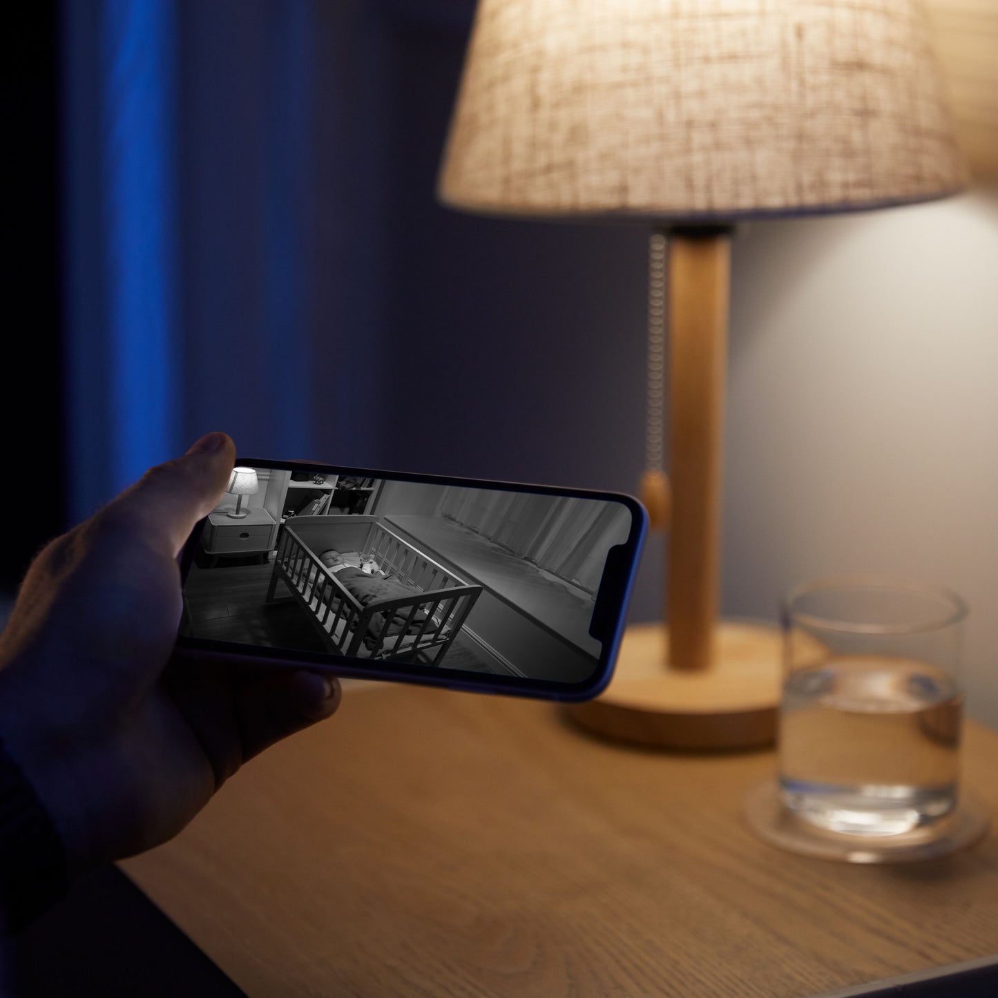 Eufy Indendørs kamera 2K Pan  Tilt babyalarm vises på smartphone med sort-hvid video af sovende baby i tremmeseng.