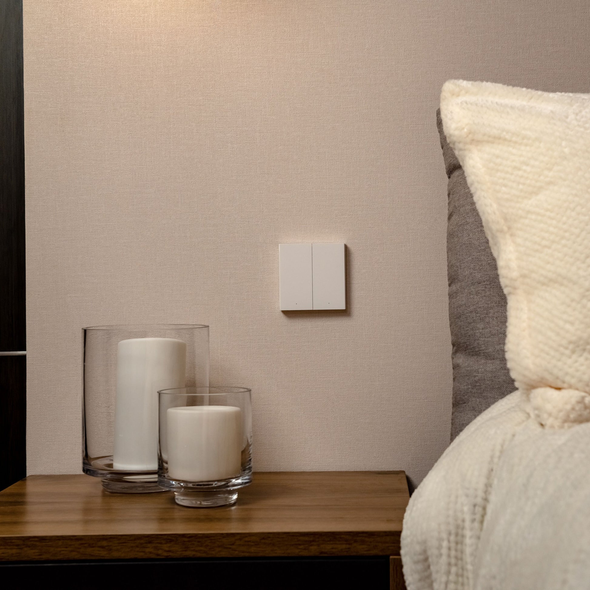 Aqara Smart Fjernbetjent Skifte H1 Dobbelt monteret på beige væg over trænatbord med hvide stearinlys i glas.