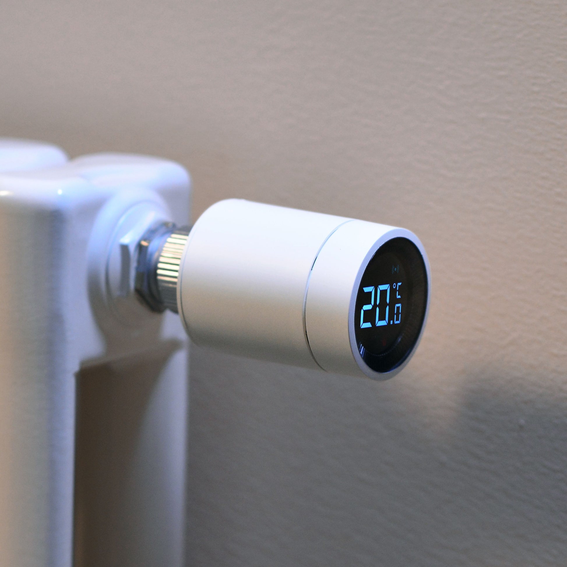 Aqara E1 Smart Termostat til radiator, monteret på hvid radiator, LED display viser 20°C, beige baggrund.