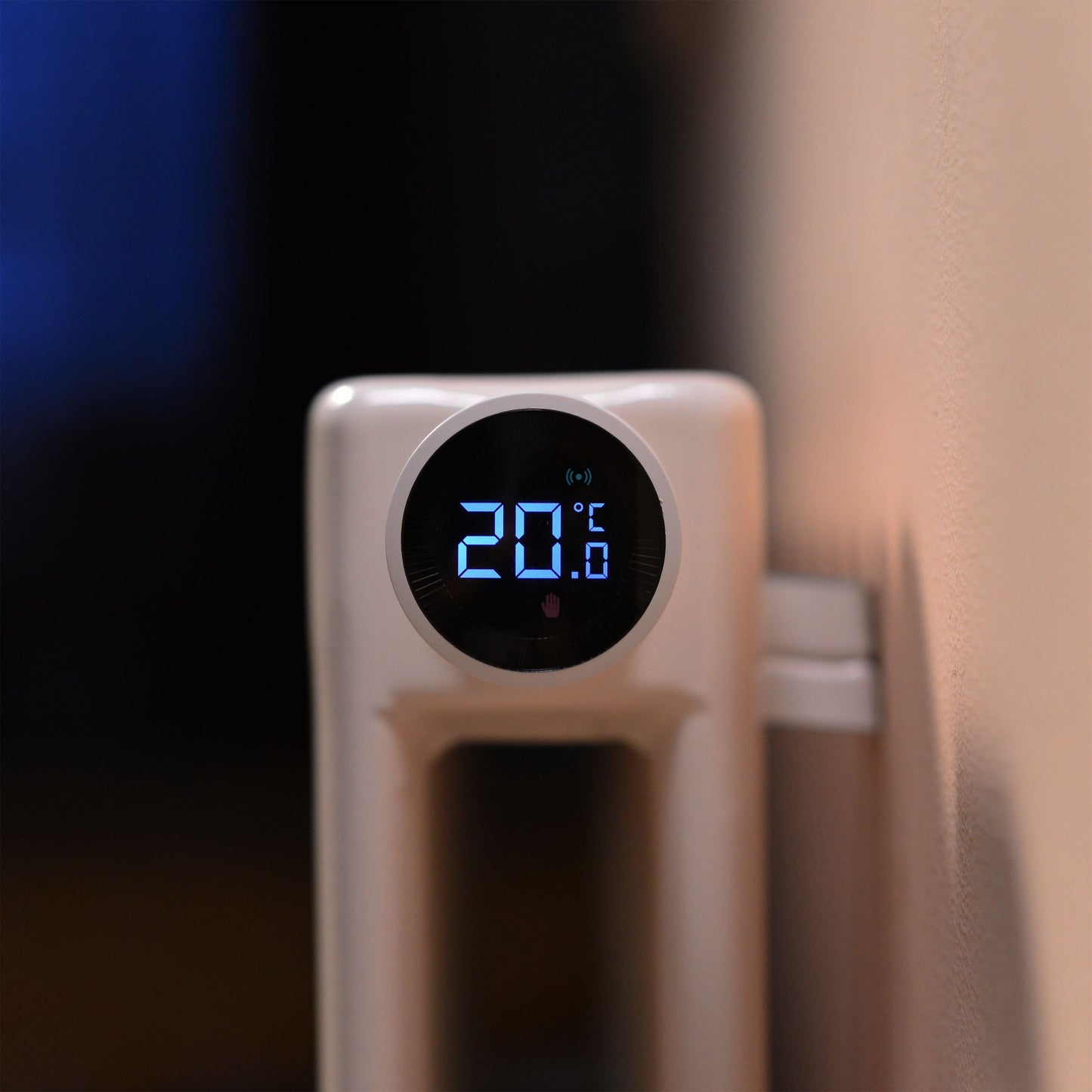 Aqara E1 Smart Termostat til radiator, monteret på radiator ved beige væg, display viser 20°C med blå tal.