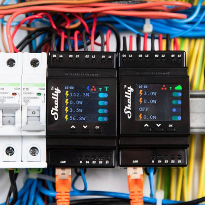 Shelly 4Pro PM DIN-fjernbetjent strømafbryder viser effekt på panel, omgivet af farvede ledninger og orange netkabler.