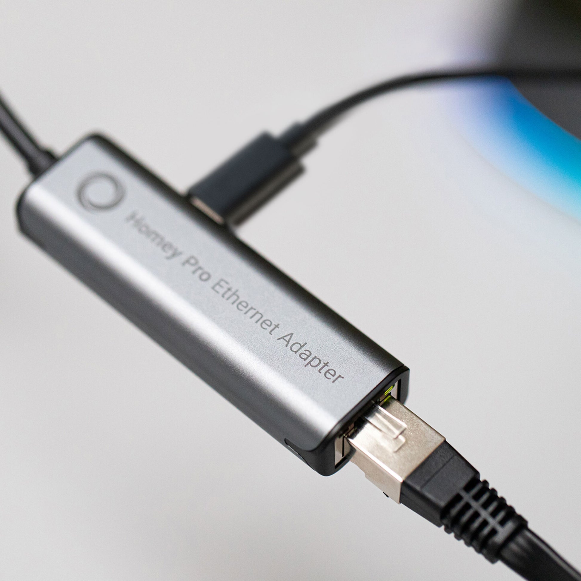 Athom Ethernet-adapter til Homey Pro tidligt 2023 med sort netværkskabel tilsluttet, close-up vinkel.
