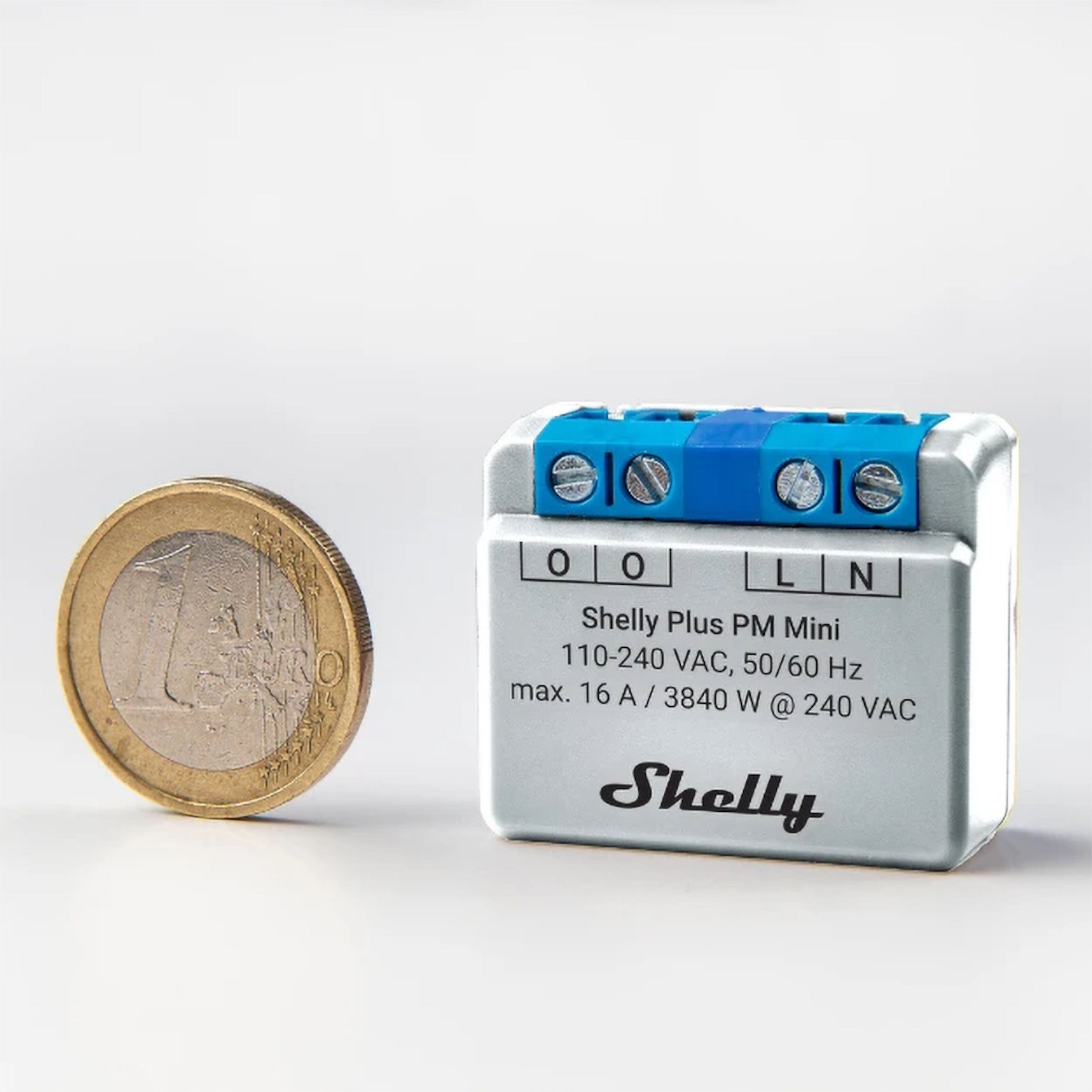 Shelly PM Mini (GEN 3) WiFi energimåler med synlige specifikationer og elektriske terminaler på toppen ved siden af euromønt.