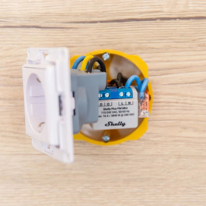 Shelly PM Mini GEN 3 WiFi effektmåler i gul el-boks med synlige ledninger monteret på trævæg.