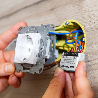 Shelly PM Mini GEN 3 smart relæ, wifi energimåler monteret bag vægudtag, ledninger tilsluttet terminaler.