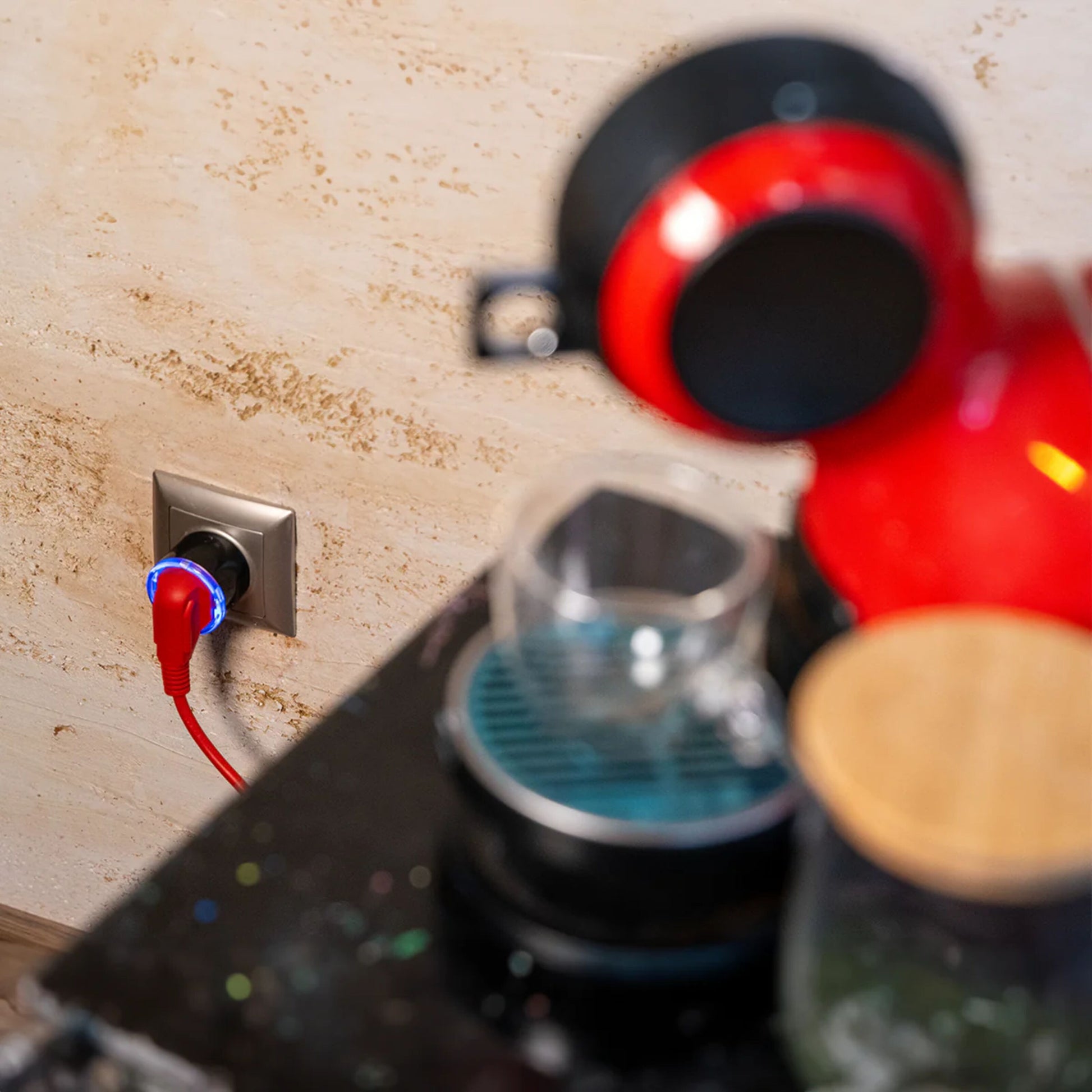 Rød kaffemaskine med ledning tilsluttet Sort Shelly Plug S Gen3 smart stik, klar glas kop ved siden af.