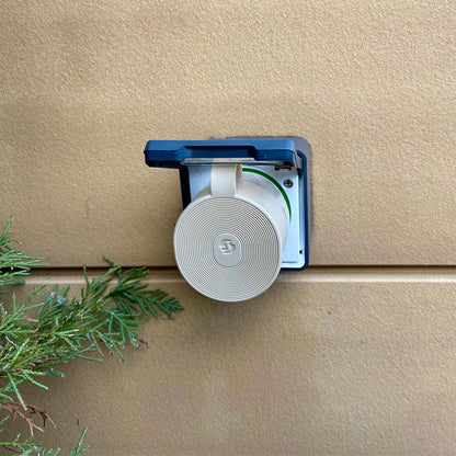 Shelly Outdoor Plug S Gen3 smart udendørskontakt Mocha i stikdåse, blå dæksel over, grønt blad nederst til venstre.