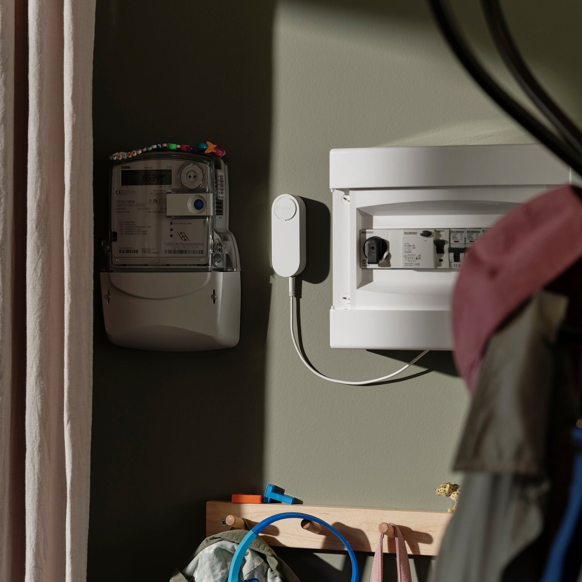 Tibber Pulse CT realtidsmåler med lastbalancering Startpakke og digitale elmåler monteret på grøn væg.