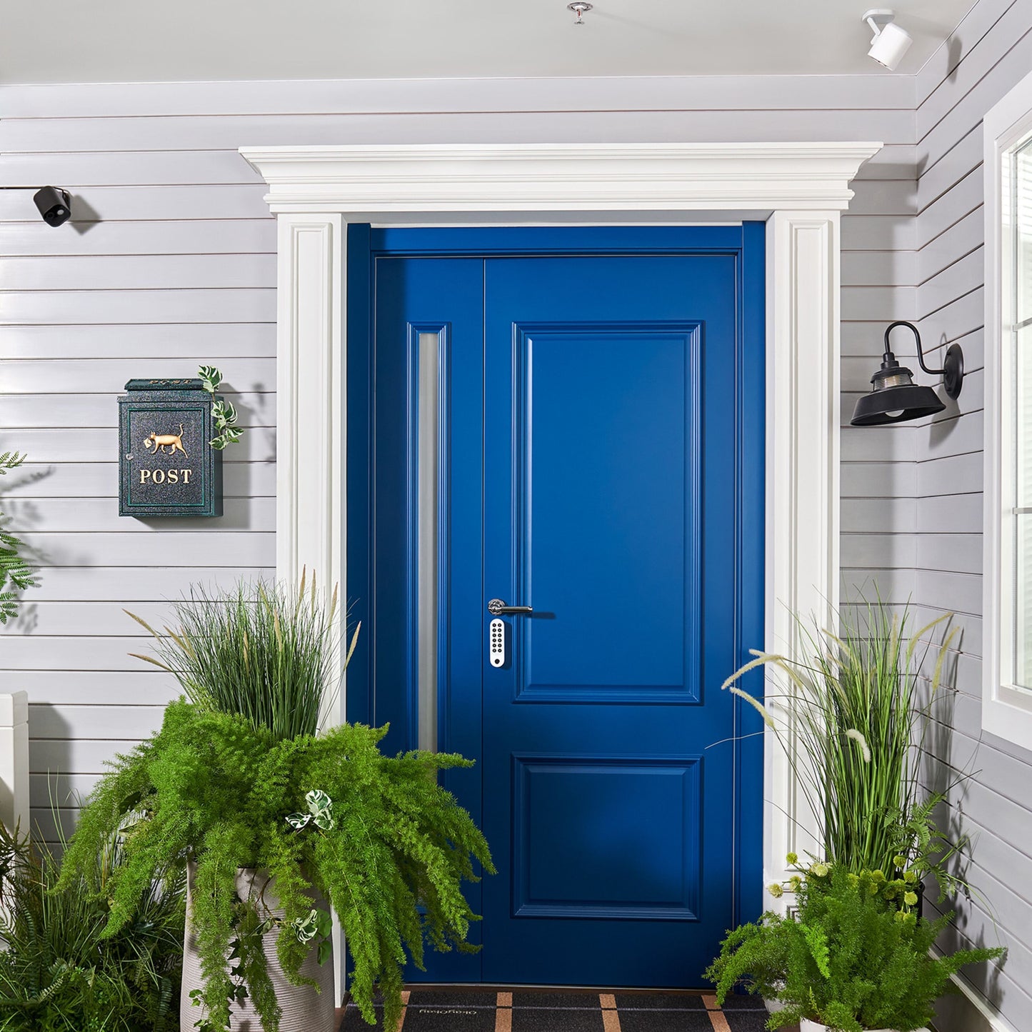 Aqara Camera Hub G5 Pro WiFi Hvid monteret ved grå husvæg, synlig blå dør, POST-postkasse, lanterne.