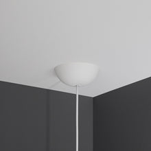 Cablecup Klassisk loftroset hvid Ø158 mm med ledning monteret i hjørnet mellem hvidt loft og to mørkegrå vægge.
