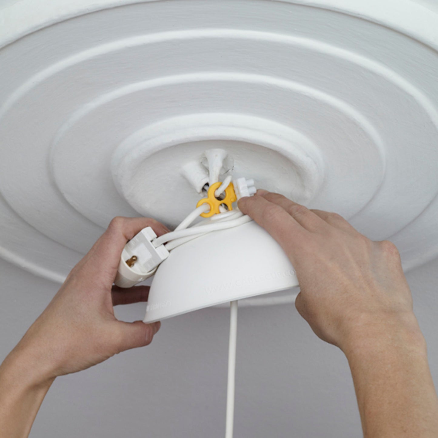 Cablecup Lille hvid Ø125 mm installeres på loft med synlige ledninger og hvid rosette.