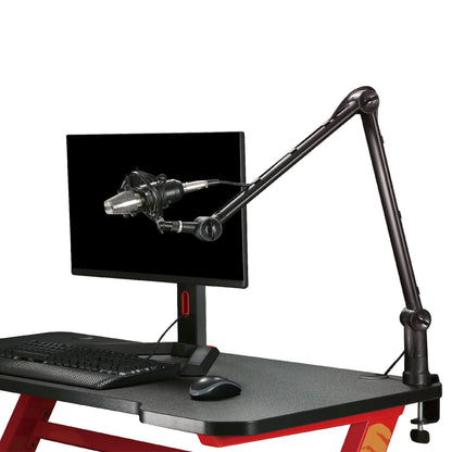 Nikabe Mikrofonarm Pro mikrofonarm monteret på rød og sort skrivebord, synligt med mikrofon, monitor, tastatur, mus.