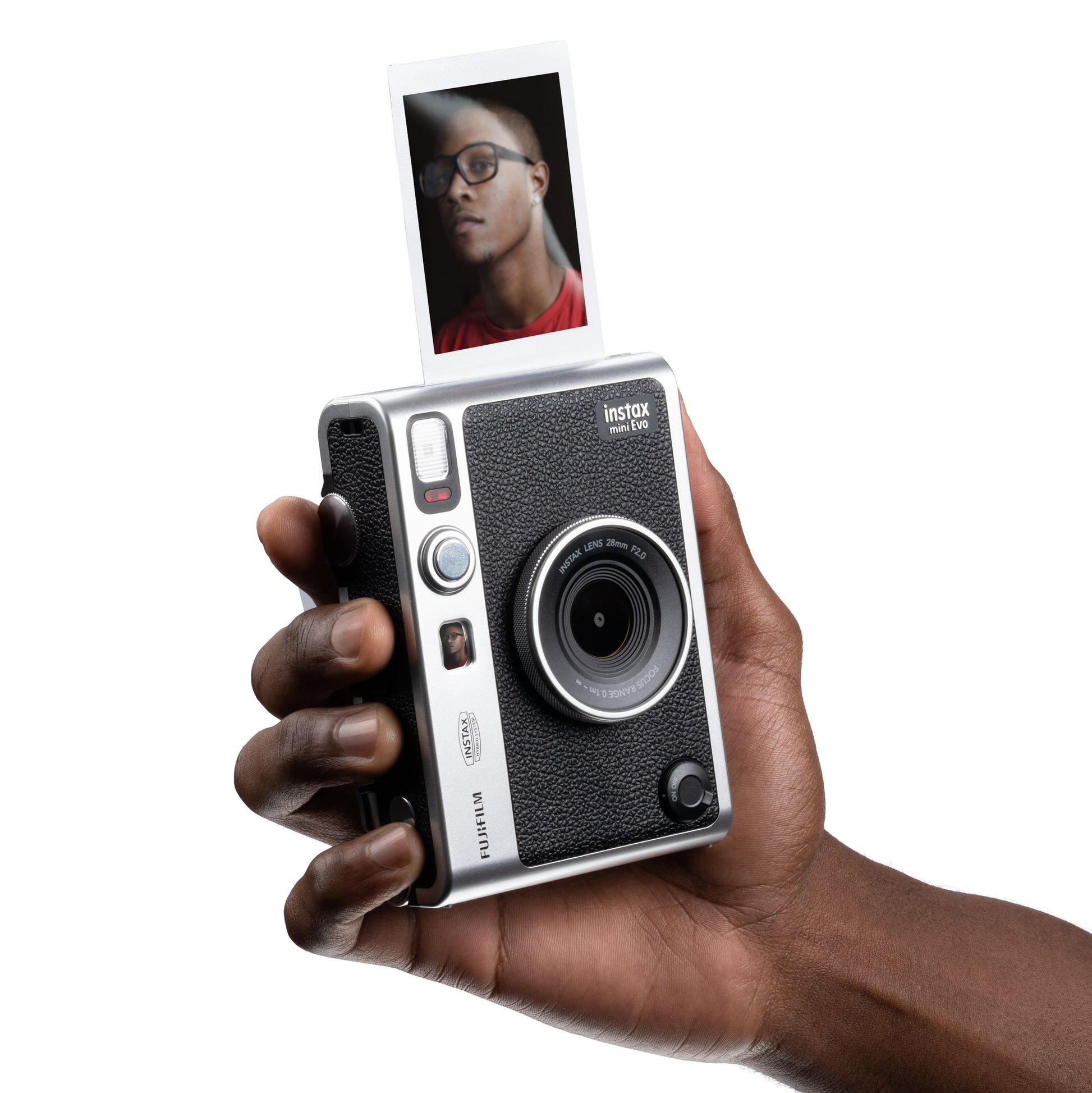 Fujifilm Instax Mini Evo Sort instant kamera holdes i hånden, foto af person med briller og rød trøje udskrives.