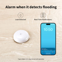Aqara T1 lækagedetektor på vådt trægulv ved siden af smartphone med notifikation om lækage registreret.