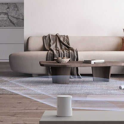Aqara bevægelses- og lyssensor AS5 hvid på lavt sofabord i stue, synlig beige sofa og trætone, kompakt design.