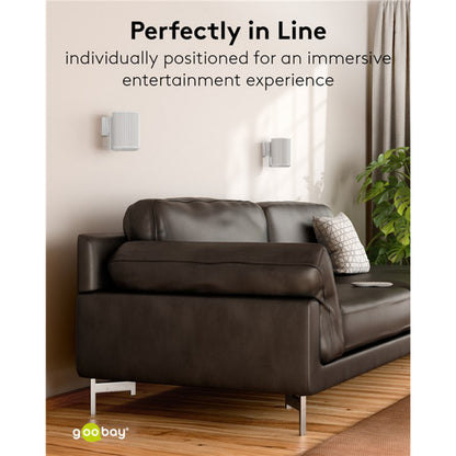 Sonos Era 100 hvid, to stk. vægmonteret med 2-pak beslag, synlig brun lædersofa og sidebord med bog og plante.