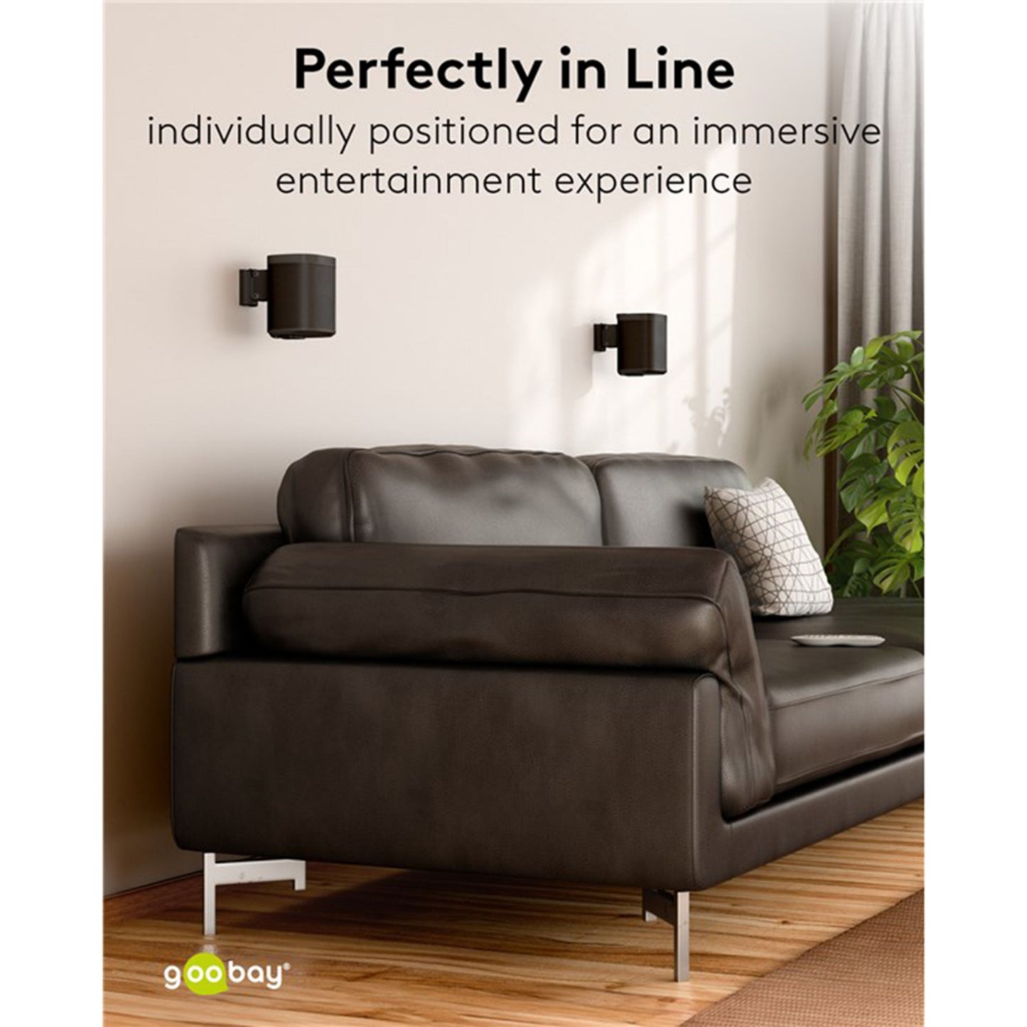 Sonos One SL sort par monteret på Goobay 2-pak beslag ved siden af mørk lædersofa og mønstret pude.