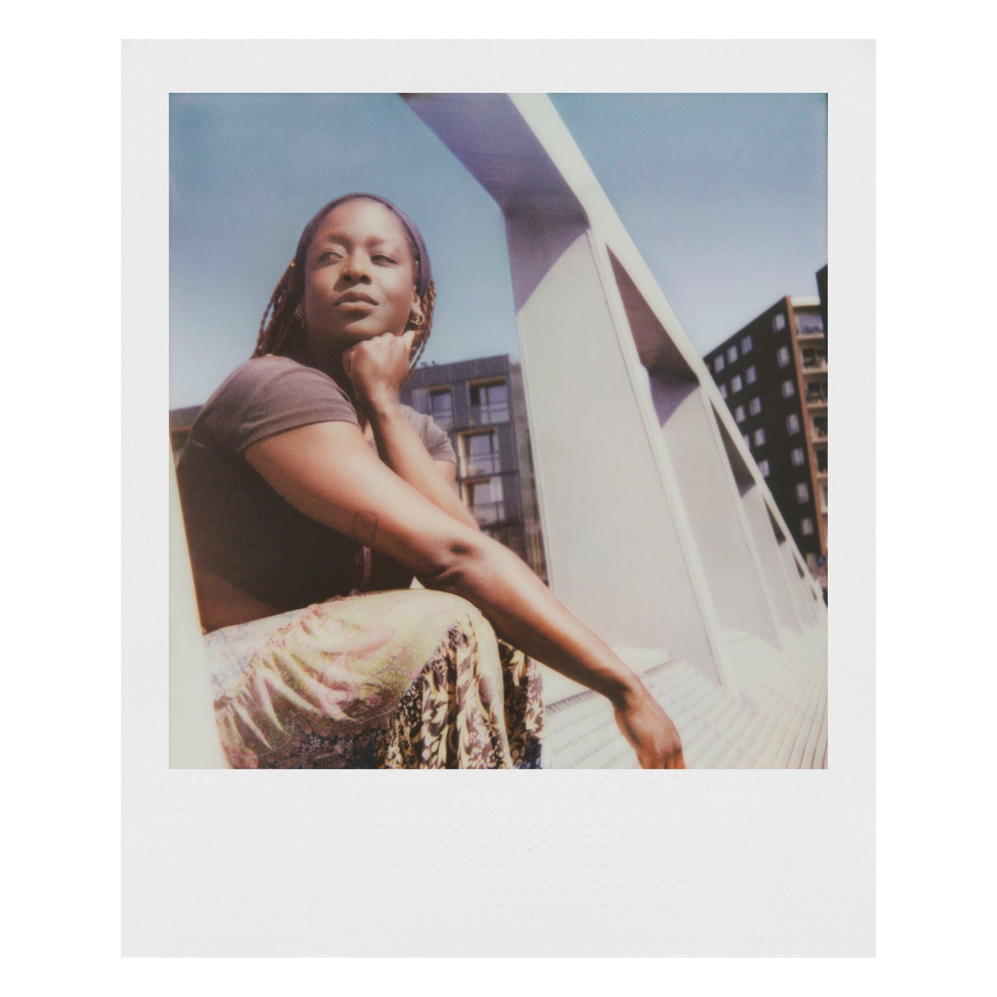 Polaroid Now Gen 3 Sort med film ligger ved siden af kvinde udendørs, kamera og emballage tydeligt synlige.
