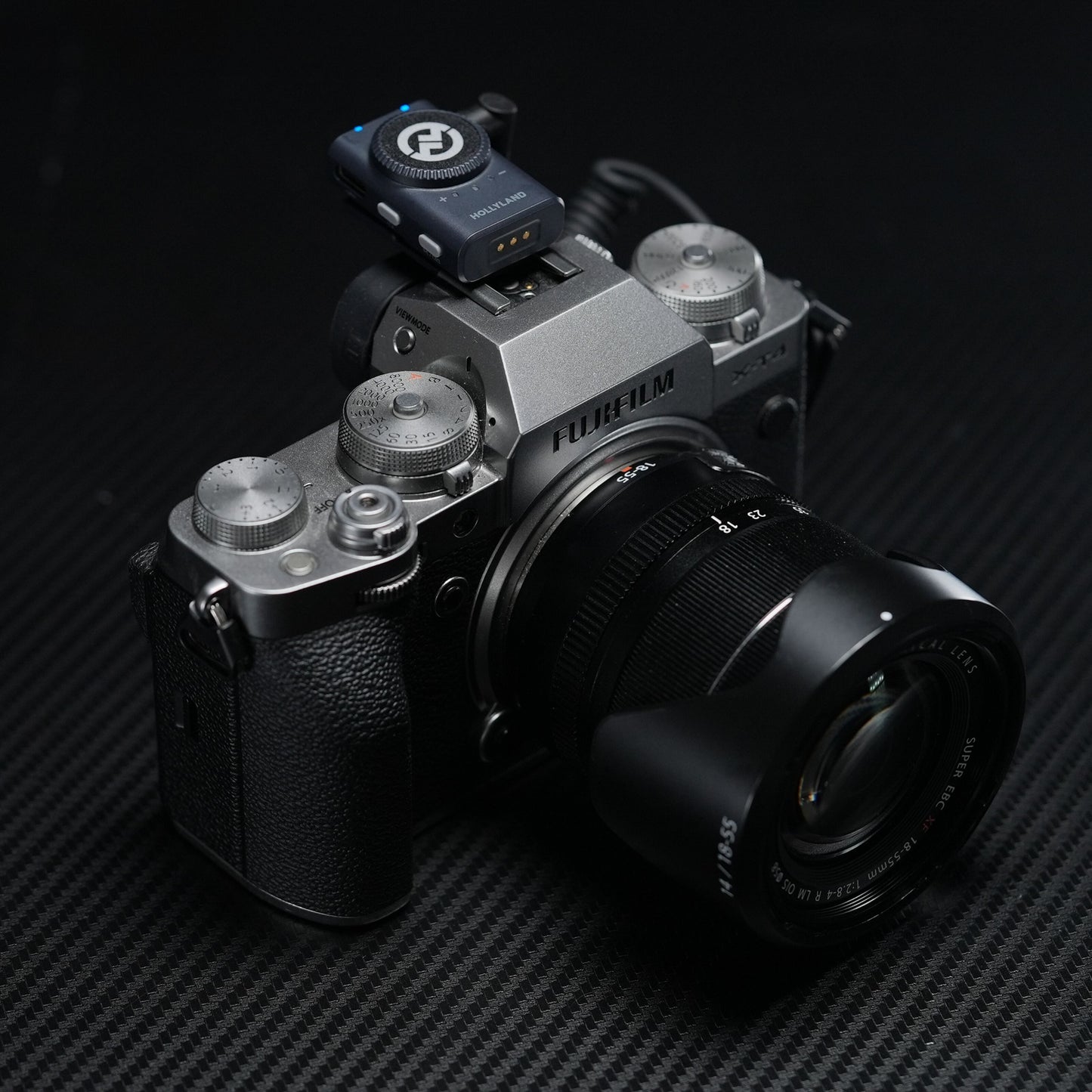 Fujifilm X-T4 med 18-55mm f/2.8-4 objektiv og Hollyland Lark M2 Combo trådløs mikrofonmodtager på hotshoe, sort baggrund.