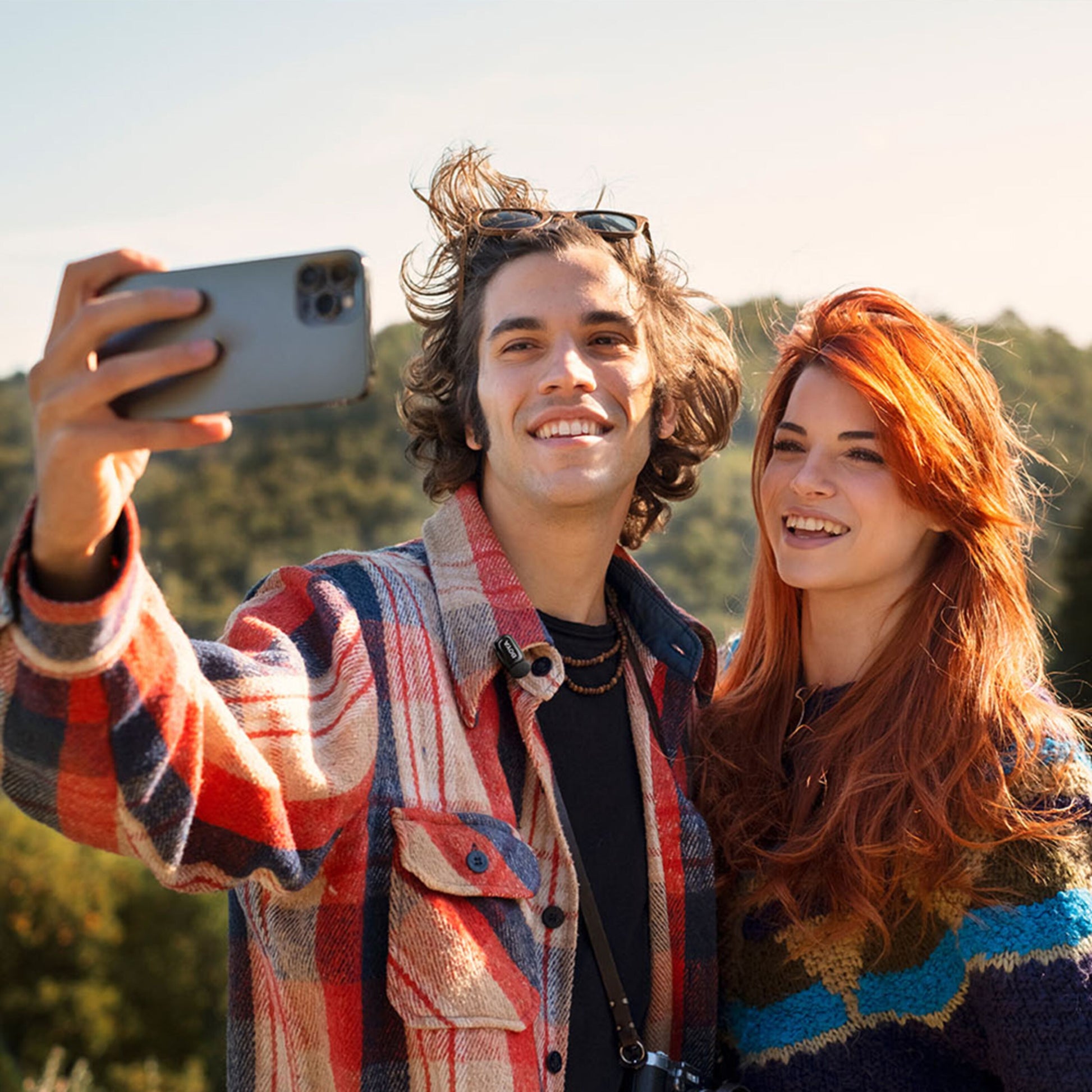 Boya mini 2 trådløst mikrofonsystem brugt til selfie med iPhone, to unge voksne, farverige jakker, udendørs.