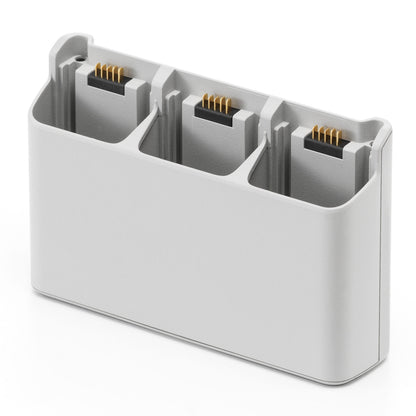 DJI Neo opladningsstation, lys grå, tre slots til små rektangulære batterier, guldstik.