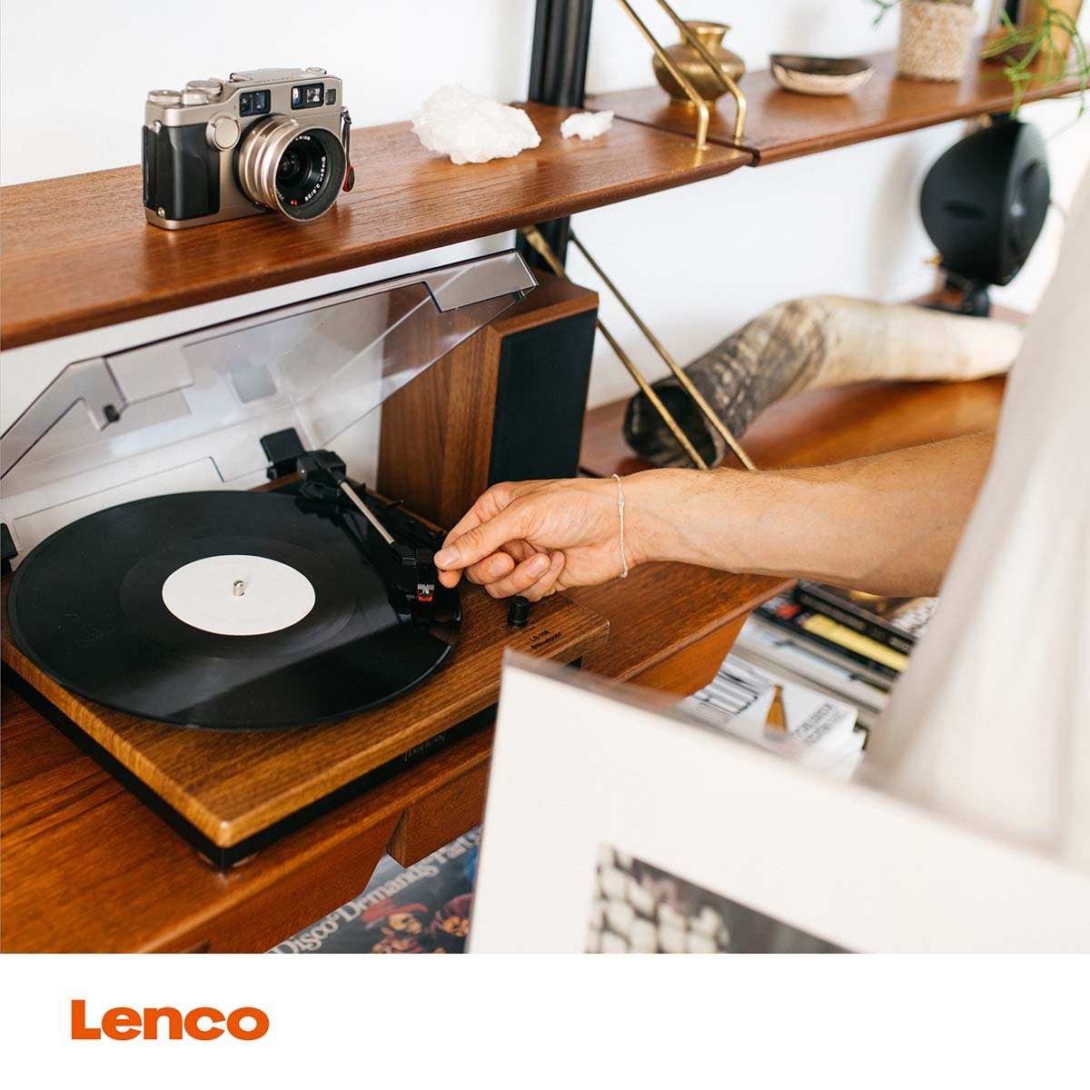 Lenco Pladespiller med Bluetooth, justeres ved nålen, orange Lenco-logo nederst, placeret på træhylde.