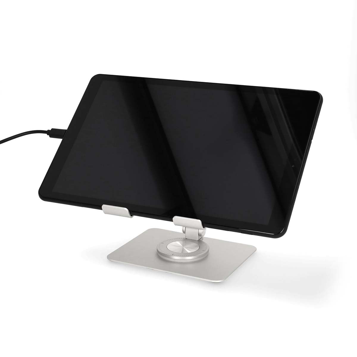 Tablet med sort skærm på sølv tabletstativ, tilsluttet opladerkabel.