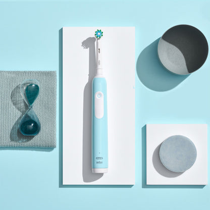 Oral-B Pro 1 DUO elektrisk tandbørste 2-pak med grå skål, grå rund genstand og blåt timeglas på lyseblå baggrund.
