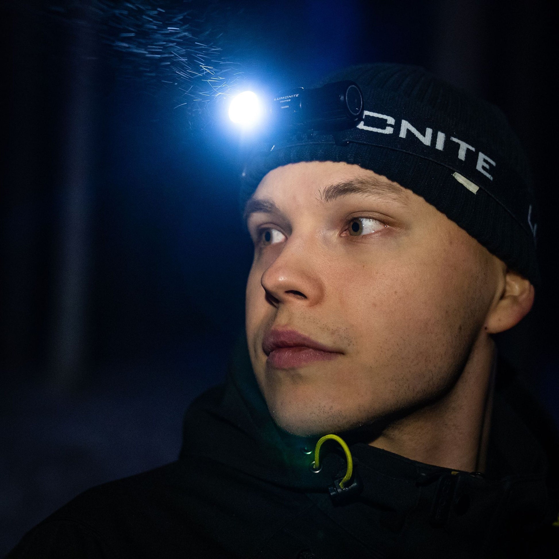 Lumonite Vector V2 pandelampe 500 lm IPX8 vandtæt bæres udendørs om natten af person med sort beanie, lys på ansigt.