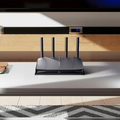 TP-Link Archer GE230 WiFi 7 gamingrouter sort med fire antenner, op til 3600 Mbps, notebook synlig ved siden af.