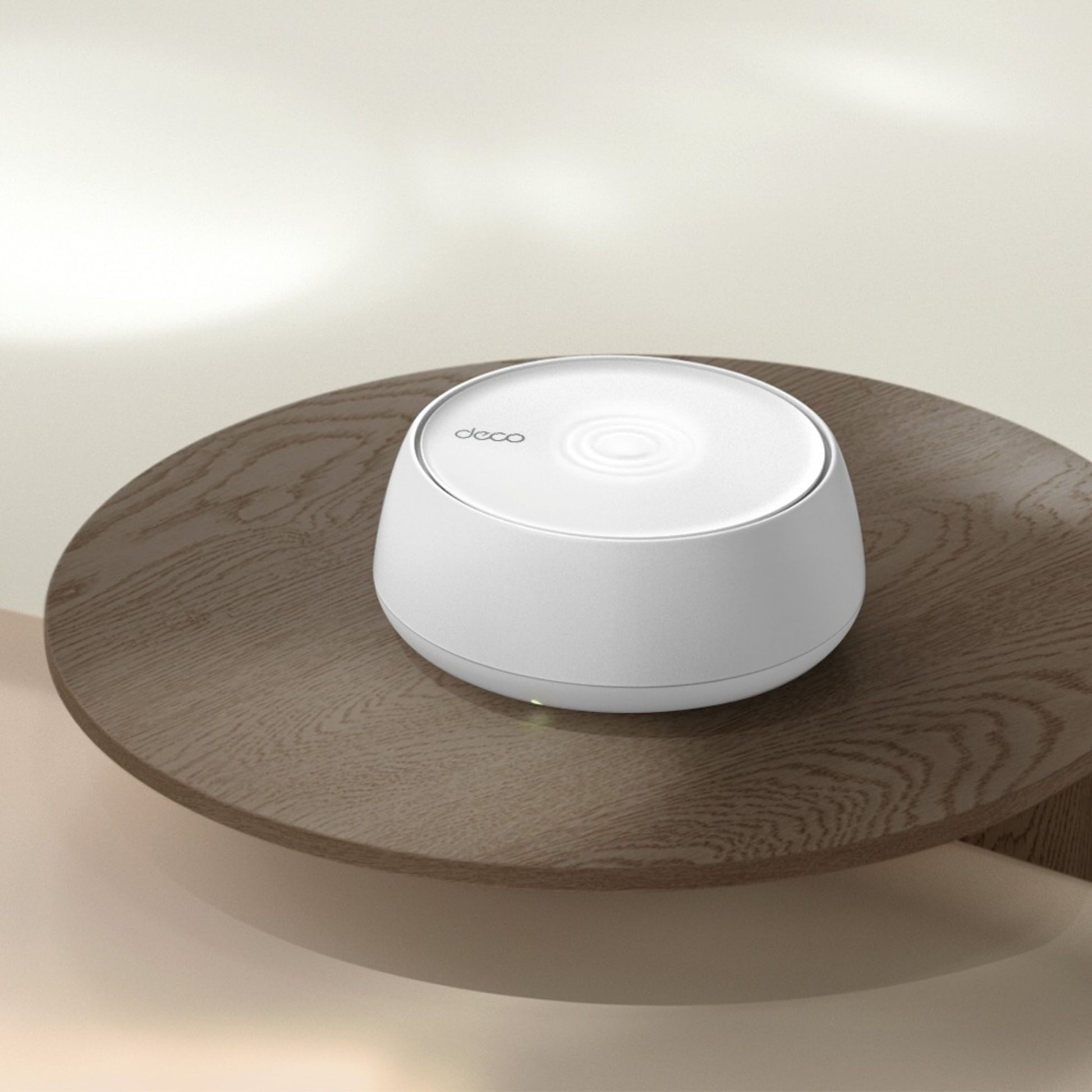 Tp-Link Deco BE3600 Pro hvid rund dual-band mesh router på lyst rundt træbord.