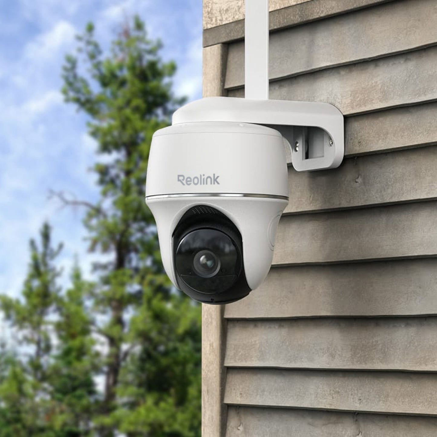 Reolink Go Series G430 udendørs 4G LTE kamera 2K monteret på bygning, træer og blå himmel baggrund.