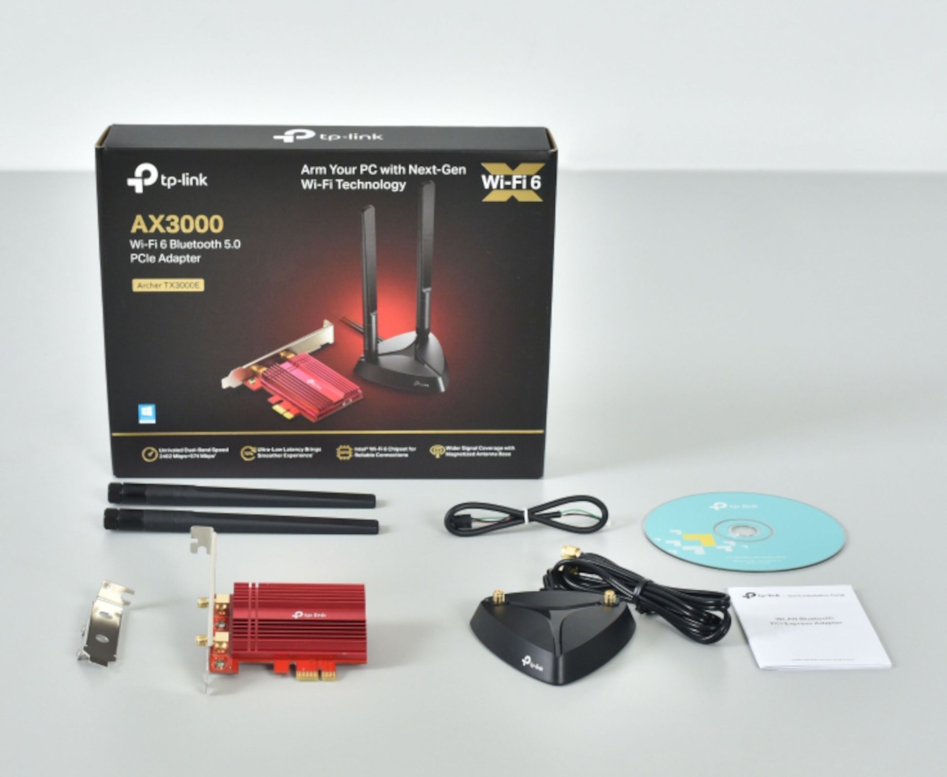 TP-Link Archer TX3000E AX3000 PCIe netværkskort med Bluetooth 5, antenner, base, kabler, CD, brugervejledning og æske.