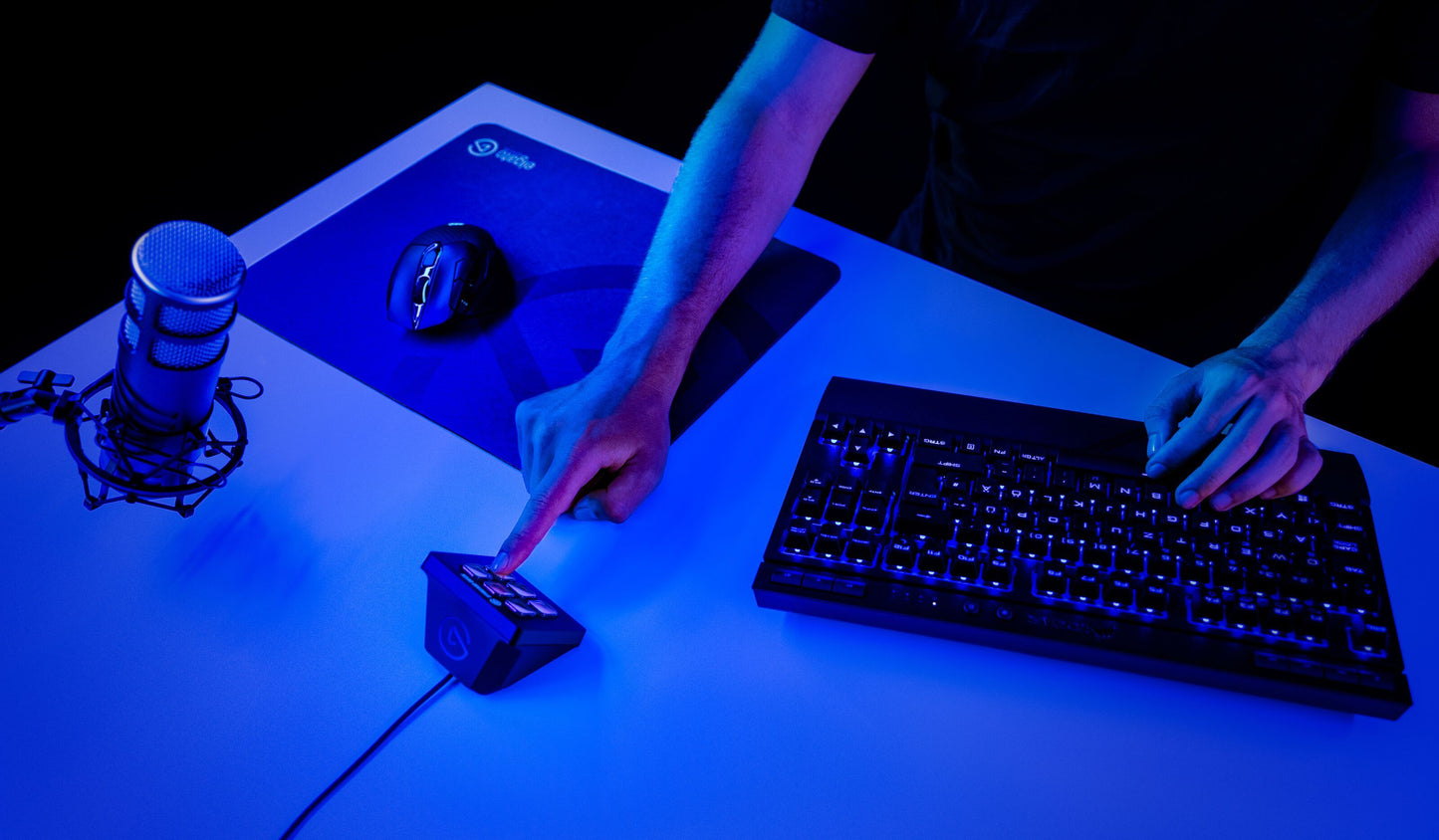 Elgato Stream Deck Mini programmerbart tastatur med LCD-taster på blåt oplyst skrivebord med bagbelyst USB-tastatur og gamingmus.