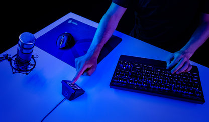 Elgato Stream Deck Mini programmerbart tastatur med LCD-taster på blåt oplyst skrivebord med bagbelyst USB-tastatur og gamingmus.