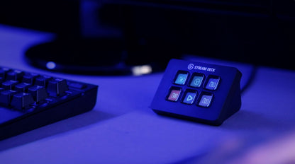Elgato Stream Deck Mini programmerbart tastatur med 6 blå oplyste LCD-taster, vist på skrivebord ved siden af tastaturet.