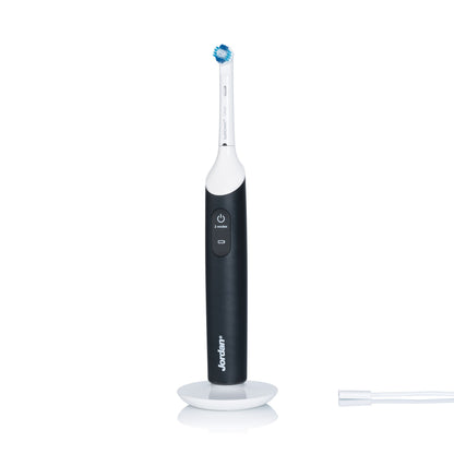 Jordan Clean Smile Plus elektrisk tandbørste med lille rundt børstehoved, synlig power-knap og brandnavn på opladerstation.