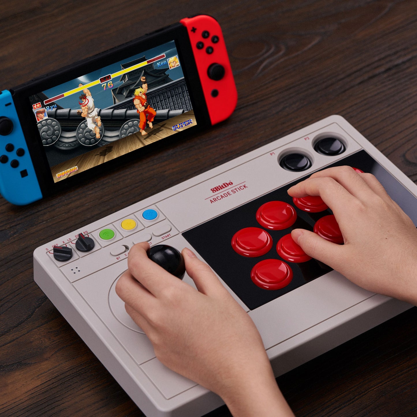 8Bitdo Arkade joystick brugt med Nintendo Switch, kampspil på skærmen, produkt på træbord.