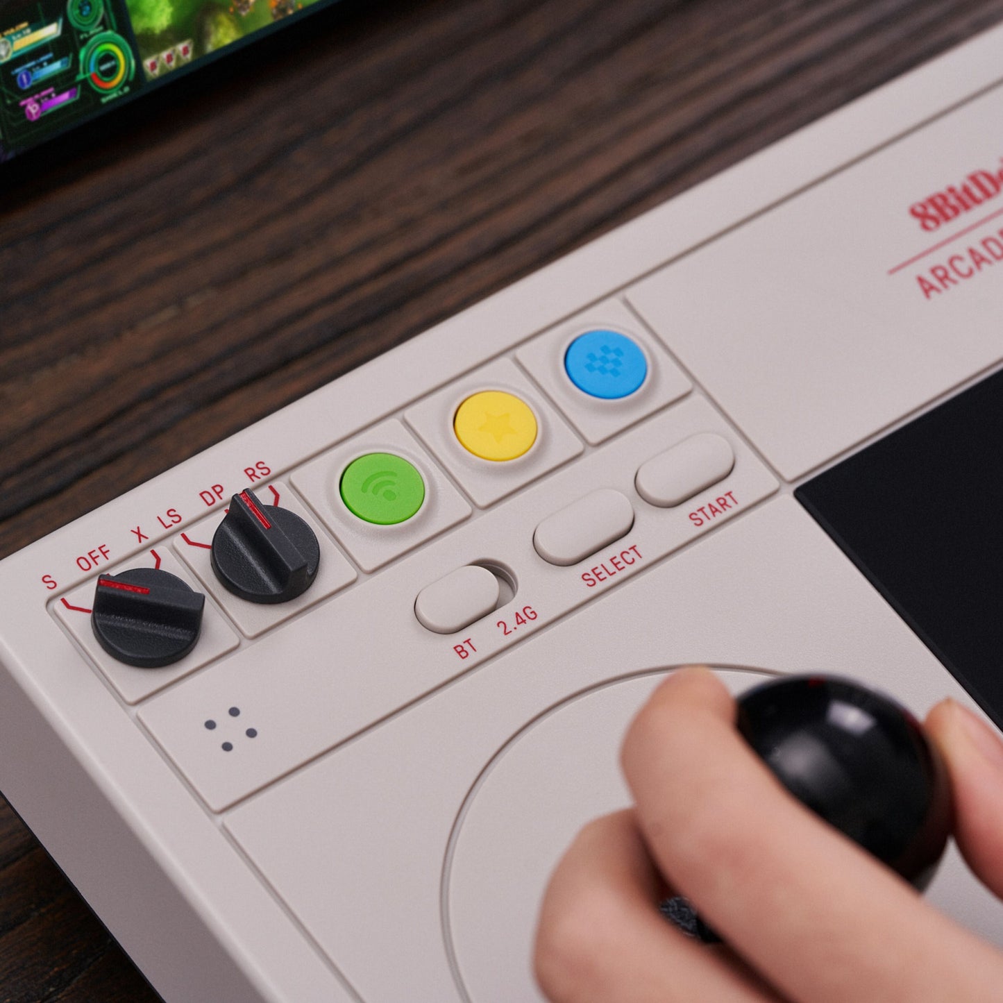 8Bitdo Arkade joystick hvid trådløs controller med farvede knapper, til runde kontakter og arkadestik, skærm i baggrunden.